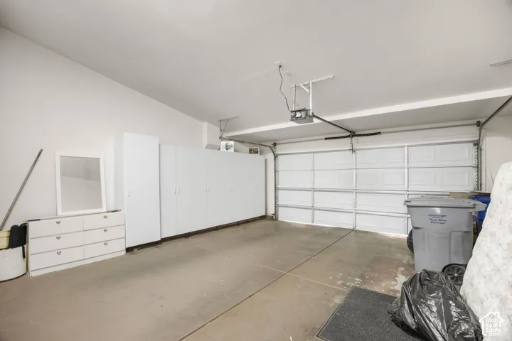 Attached garage featuring concrete flooring, an automated overhead door, and integrated wall-mounted storage cabinetry