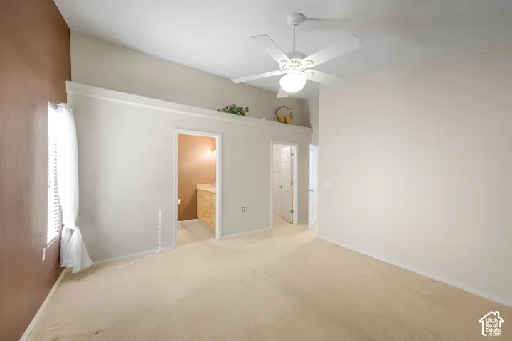 Vaulted ceilings with a central white ceiling fan and integrated lighting, featuring a recessed display ledge and neutral wall tones