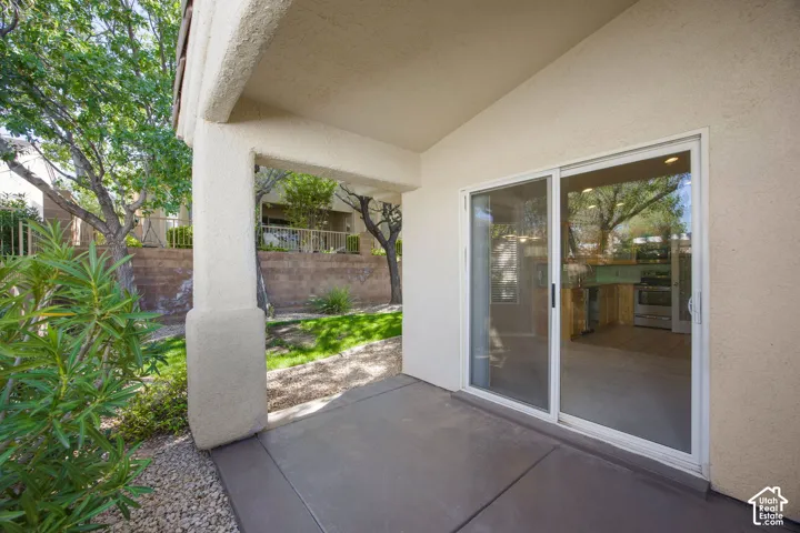 Covered patio with concrete flooring, stucco exterior finish, square structural pillar, and sliding glass door