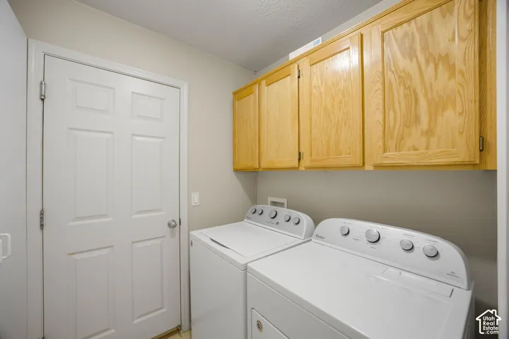 Utility room featuring overhead wood-finish cabinetry, a white six-panel door, and laundry hookups