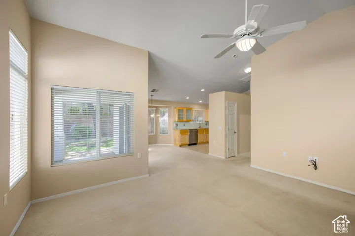 Vaulted ceilings featuring a white ceiling fan with integrated lighting, large windows with horizontal blinds, and neutral wall tones