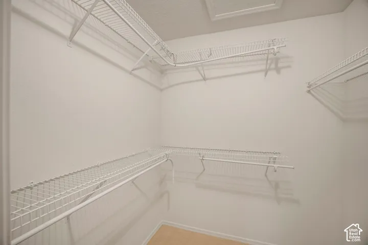 Walk-in storage space featuring multi-tiered white wire shelving and integrated hanging rods