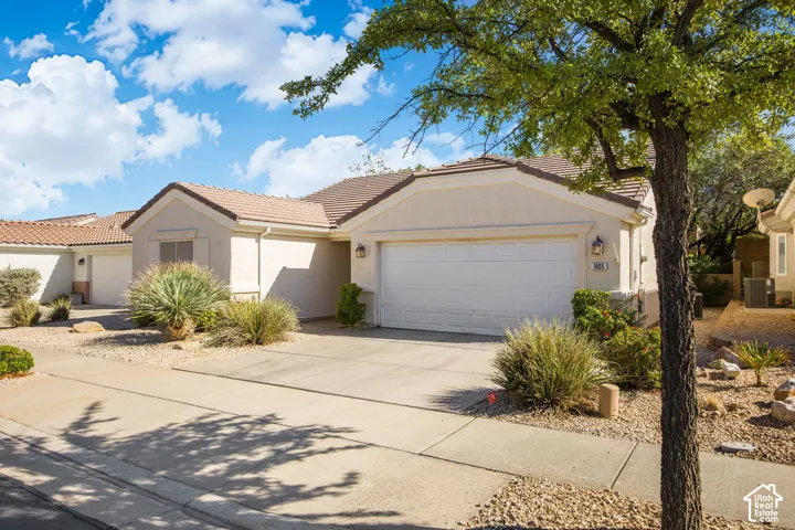 Stucco exterior with a tiled roof, multi-car garage, and low-maintenance desert landscaping