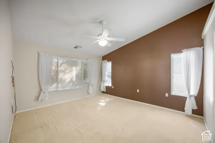 Vaulted ceilings, neutral carpeting, and a central ceiling fan with integrated lighting