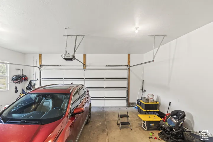 Multi-vehicle garage featuring a paneled sectional door, concrete flooring, and an automated overhead door opener