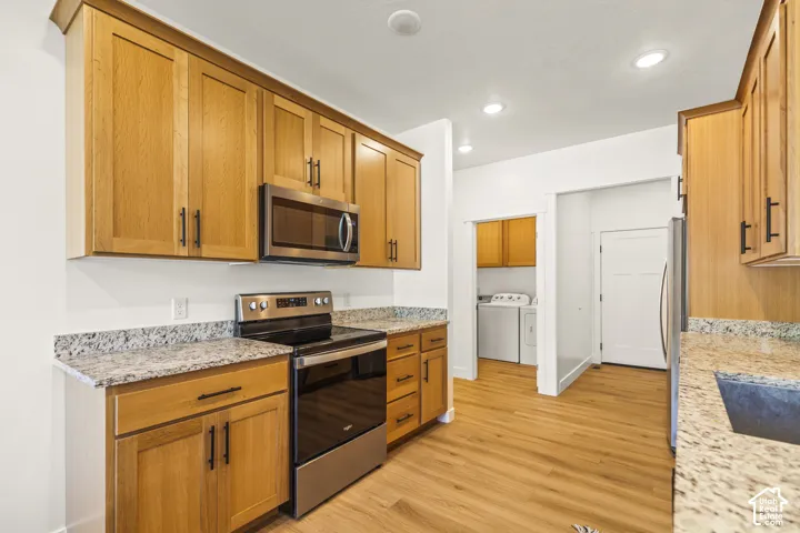 Kitchen featuring wood cabinetry, stone-finish countertops, stainless steel appliances, wood-finish flooring, and recessed lighting