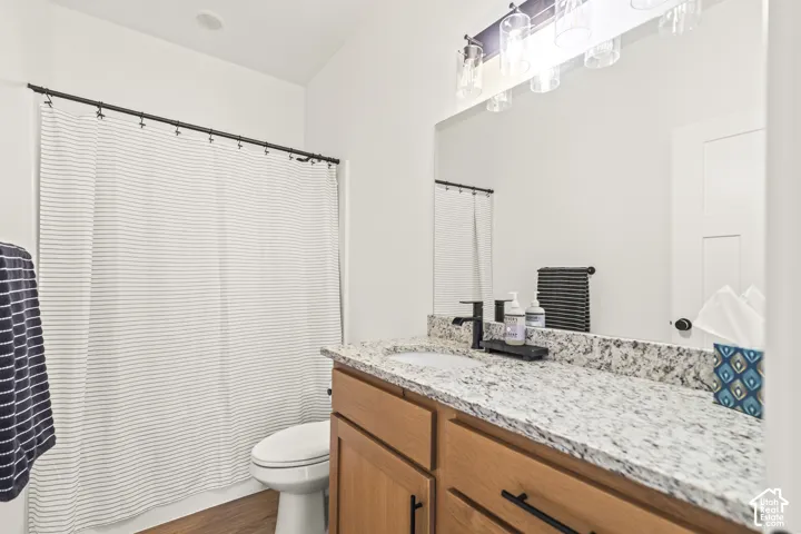 Bathroom vanity with stone-style countertop, undermount sink, and matte black hardware, featuring a full-width mirror and multi-light vanity fixture