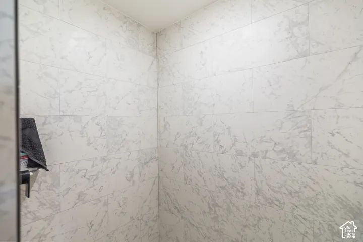 Shower stall featuring large-format, light-toned stone-patterned wall tile with a matte finish
