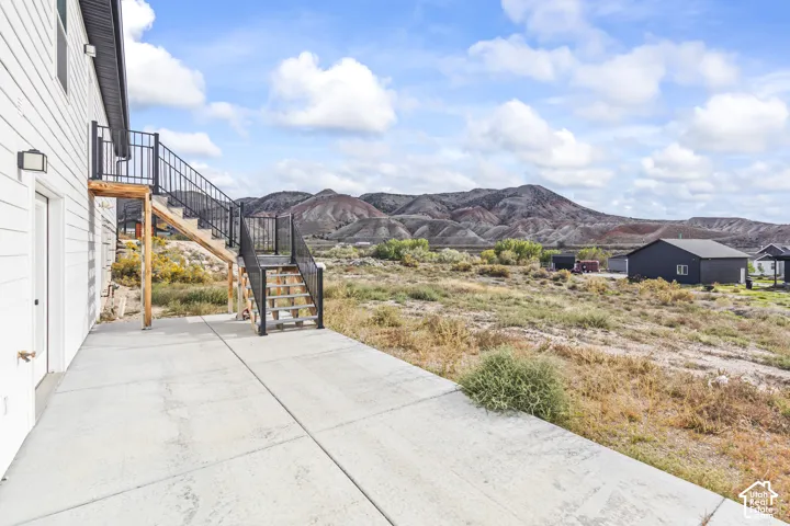 Concrete patio featuring exterior stairs with metal railings and mountain backdrop
