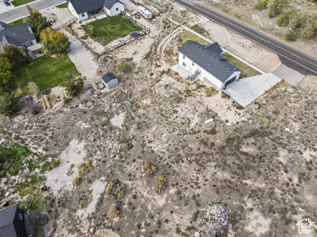 Aerial perspective of a multi-level residence featuring a multi-pitched roof, a concrete driveway, and an expansive natural lot