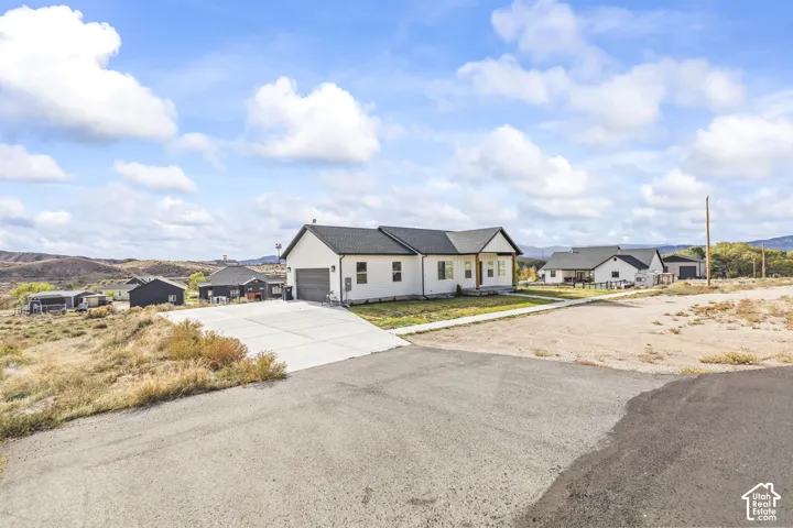 Single-level residence featuring white siding, asphalt shingle roof, attached garage, concrete driveway, and covered front porch entrance