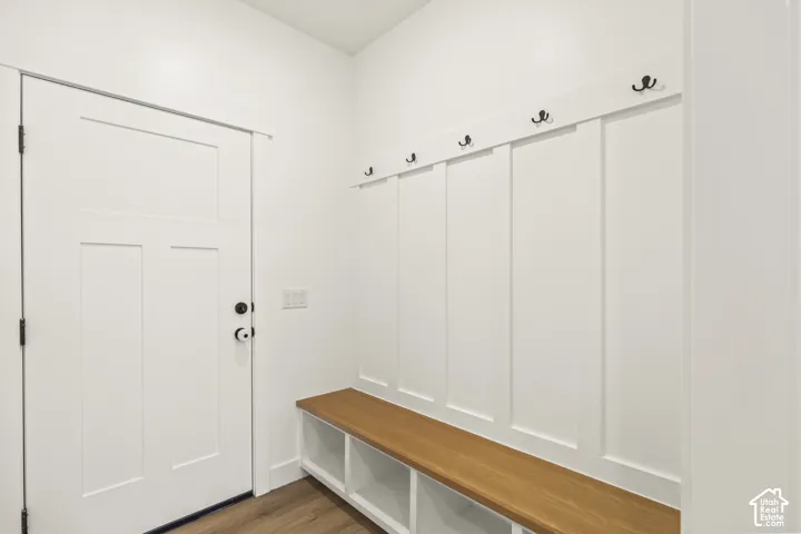 Built-in bench with wood-finish seat, integrated cubby storage, wall-mounted matte black coat hooks, and board-and-batten wall detailing