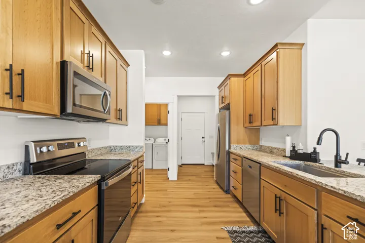 Kitchen featuring wood cabinetry, stone-finish countertops, stainless steel appliances, wood-finish flooring, and a gooseneck faucet