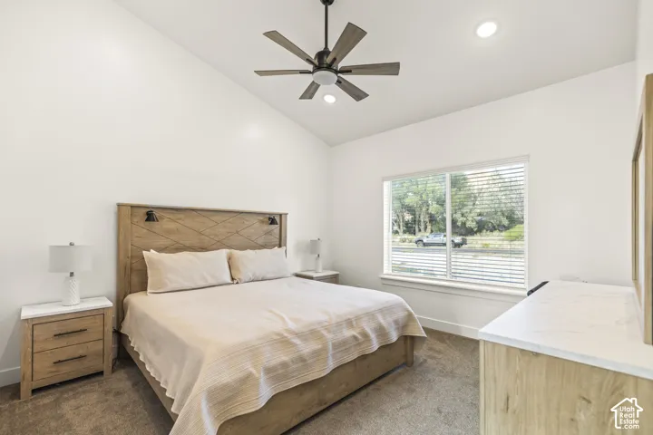 Vaulted ceiling featuring a central multi-blade ceiling fan and recessed lighting, paired with a large window