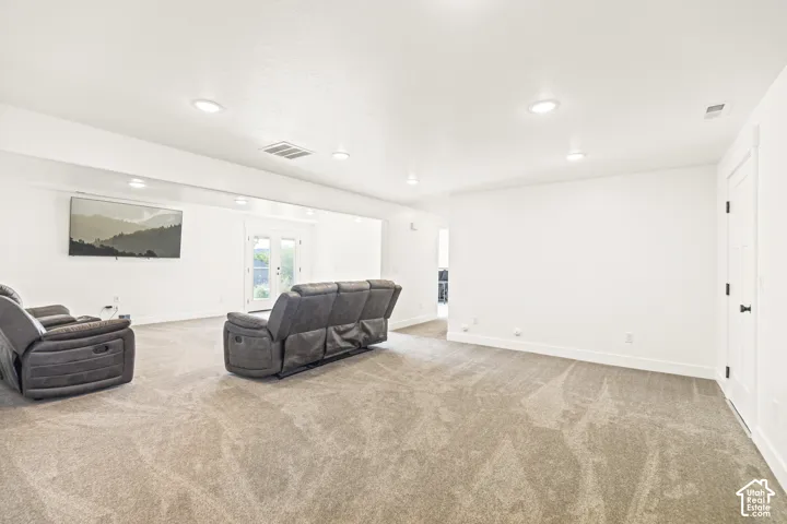 Open-concept room featuring neutral wall-to-wall carpeting, recessed ceiling lighting, and double glass-panel doors