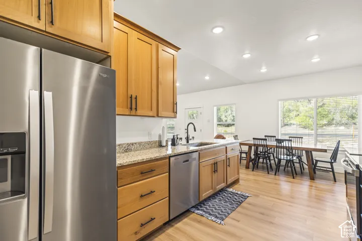 Kitchen featuring wood cabinetry, stone countertops, stainless steel appliances, wood-finish flooring, and recessed lighting