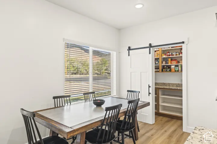 Pantry featuring a sliding barn door, stone countertop, and open shelving, paired with wood-finish flooring and a multi-pane window