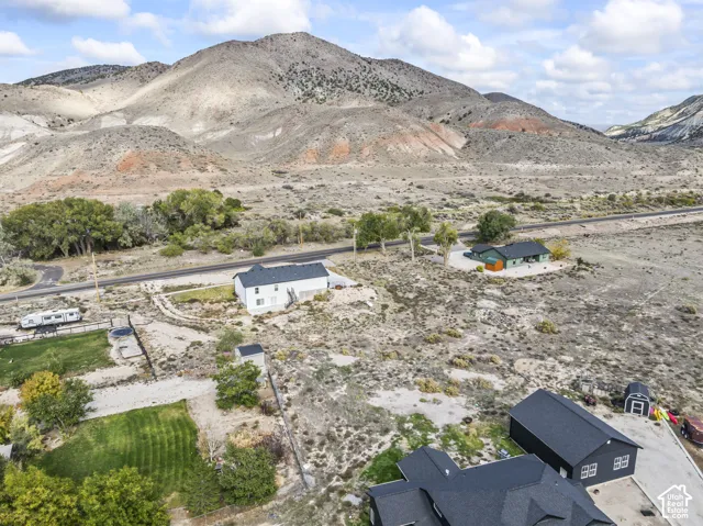 Expansive lot featuring rugged mountain backdrops, mature native trees, manicured lawn areas, and a detached garage structure