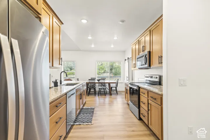 Kitchen featuring natural-finish wood cabinetry, stone countertops, stainless steel appliances, recessed lighting, and wood-finish flooring