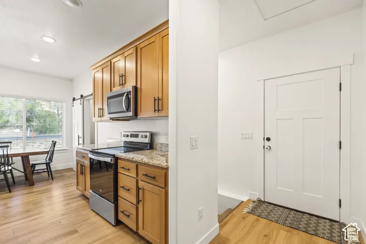 Kitchen featuring shaker-style wood cabinetry, stone countertops, stainless steel appliances, recessed lighting, and wood-finish flooring