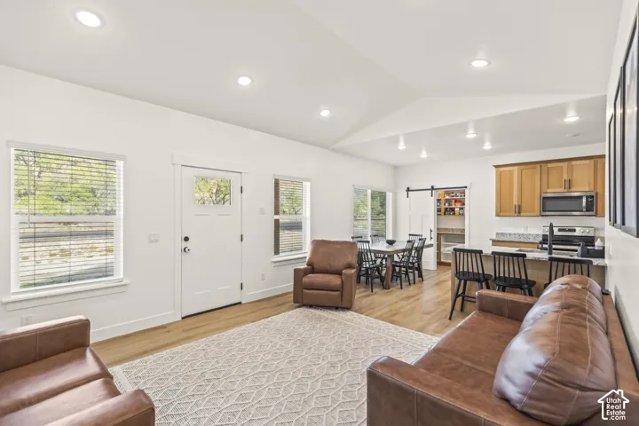 Vaulted ceilings, wood-finish flooring, recessed lighting, kitchen with quartz countertops, and a sliding barn door pantry entry