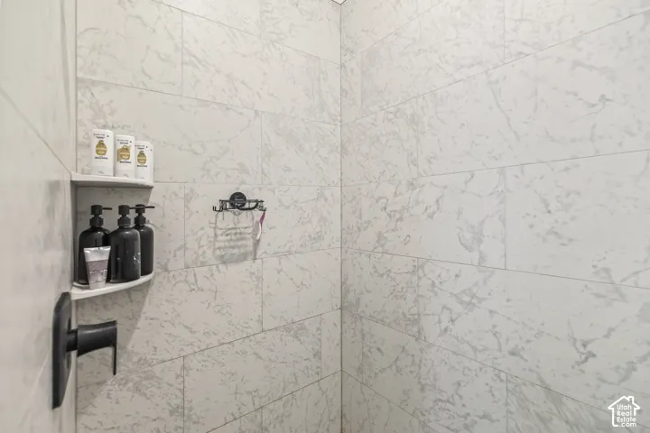 Walk-in shower featuring large-format stone-patterned tile, integrated corner shelving, and matte black fixtures