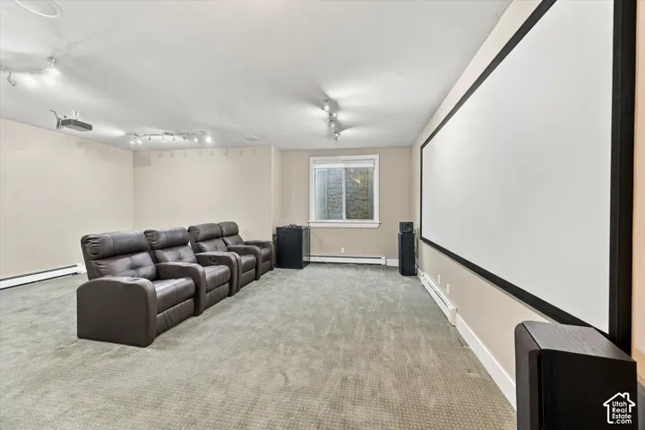 Dedicated media space featuring a wall-mounted projector screen, ceiling-mounted projection equipment, and adjustable multi-bulb track lighting