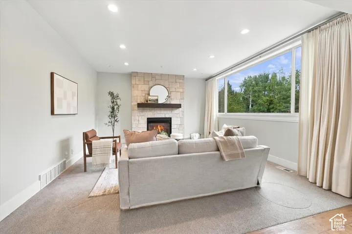 Living space featuring a stone-faced fireplace with a wood mantel, expansive picture window, and recessed lighting