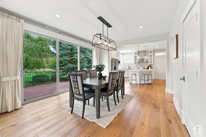 Open-concept dining area featuring wood-finish flooring, recessed lighting, and a linear four-light pendant fixture