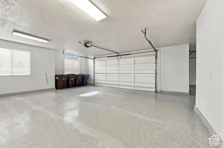 Two-car garage with finished epoxy flooring, dual overhead fluorescent lighting, and an arched window