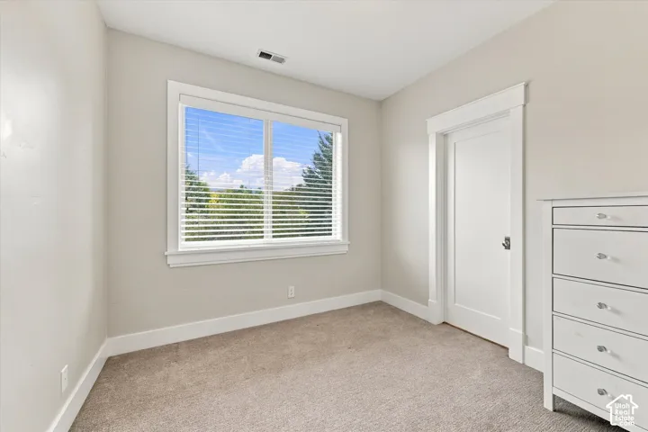 Interior room featuring neutral wall paint, high-profile door casing, large single-pane window with wood trim, and carpeted flooring