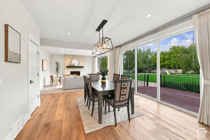 Dining area featuring wood-finish flooring, a geometric pendant light fixture, and sliding glass doors opening to a deck