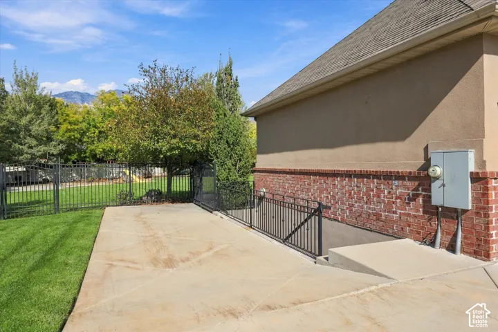 Exterior featuring a concrete side apron, brick and stucco siding, metal perimeter fencing, and a staircase with decorative metal railing