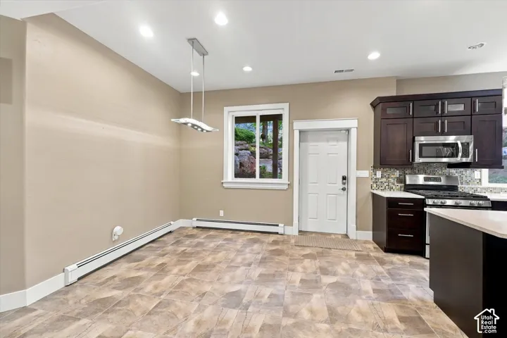 Kitchen area featuring dark-stained cabinetry, mosaic tile backsplash, built-in stainless steel microwave, recessed lighting, and patterned flooring