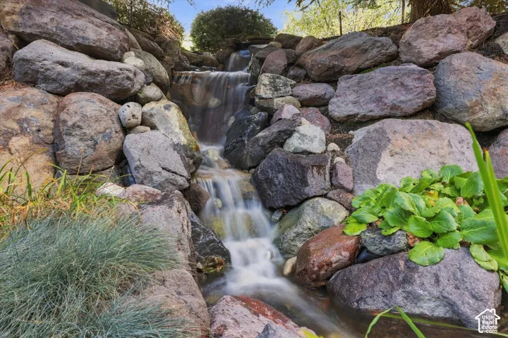 Tiered rock garden waterfall featuring natural stone boulders and integrated landscape plantings