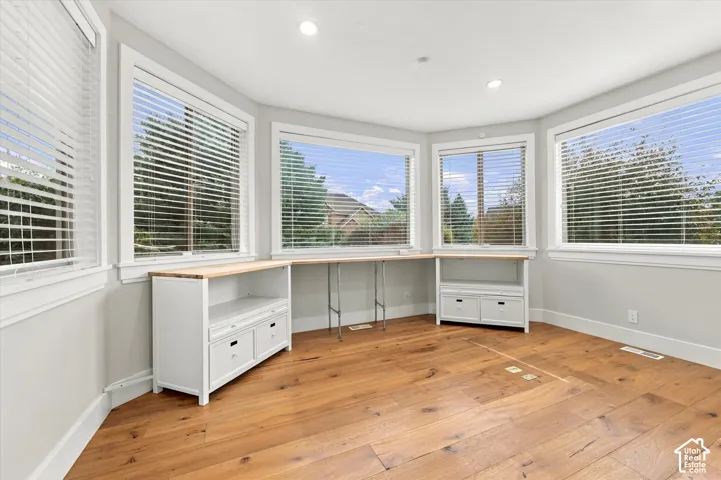 Bay area featuring expansive windows, wood-finish flooring, recessed lighting, and custom built-in cabinetry with integrated shelving