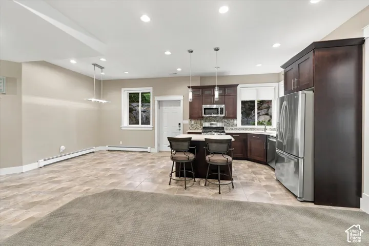 Kitchen featuring dark wood cabinetry, stainless steel appliances, a center island with a stone-surface countertop, tile flooring, and recessed lighting