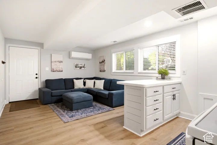 Wood-finish flooring, white built-in cabinetry with matte black hardware, horizontal plank siding detail, white paneled door, and windows with horizontal blinds