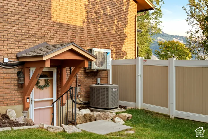 Brick exterior featuring a covered entryway with timber-frame accents, a composite privacy fence, and concrete hardscaping