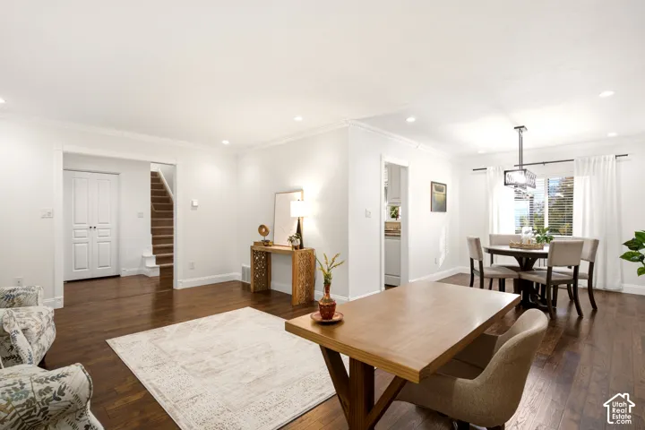 Open-concept interior featuring wood-finish flooring, recessed lighting, crown molding, and a modern box-style pendant light fixture