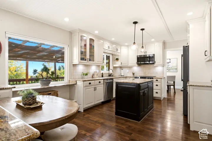 Kitchen featuring white shaker-style cabinetry, dark wood-finish flooring, a contrasting black center island, stone-surface countertops, and recessed lighting