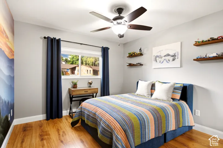 Wood-finish flooring, central ceiling fan with integrated lighting, slider window, and wall-mounted floating wood shelves