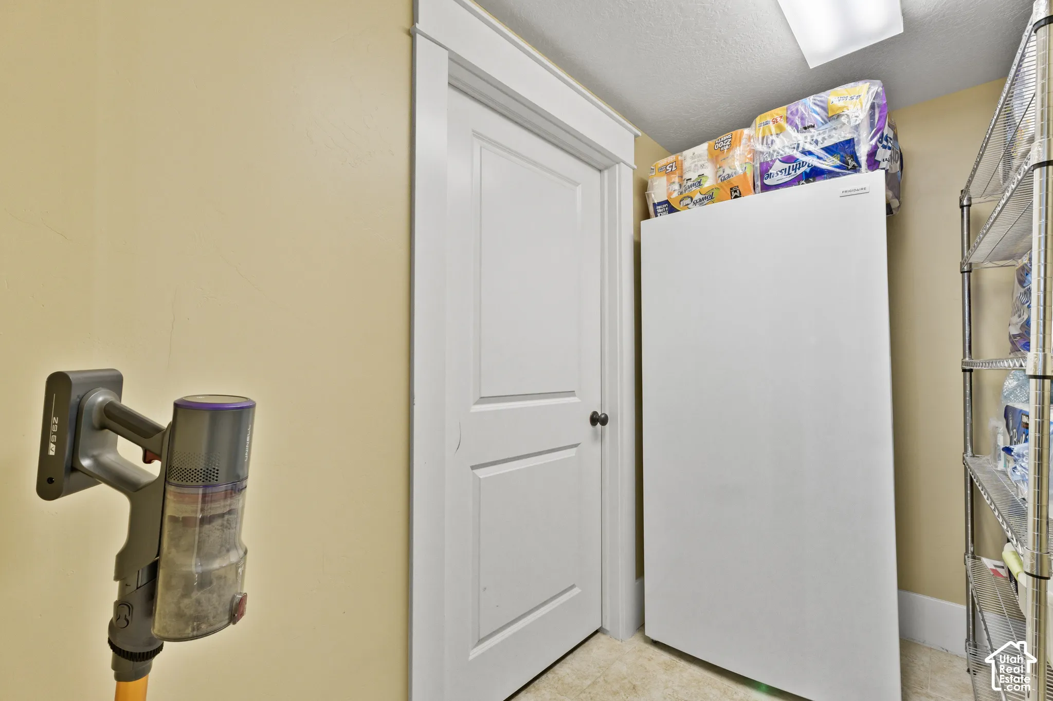 Interior space featuring a two-panel interior door with white casing, neutral-toned walls, and overhead lighting