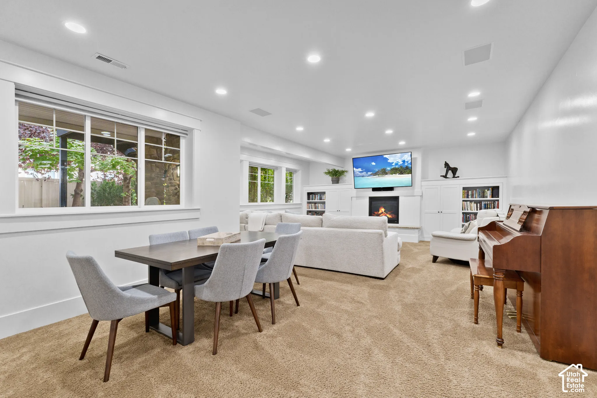 Open-concept area featuring recessed lighting, a built-in fireplace, custom white cabinetry, and large windows