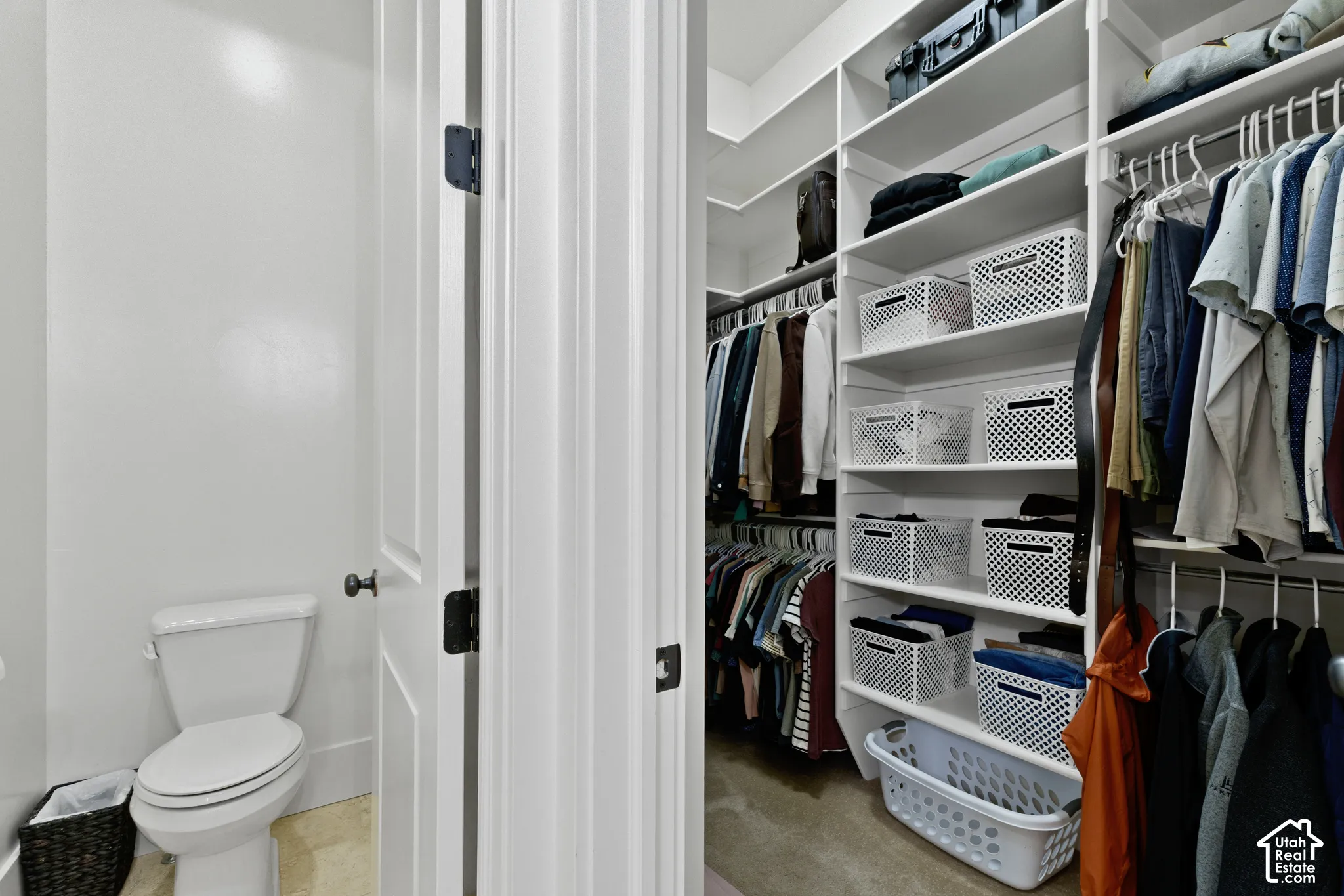 Walk-in closet featuring white floor-to-ceiling custom shelving, multiple hanging rods, and integrated cabinetry