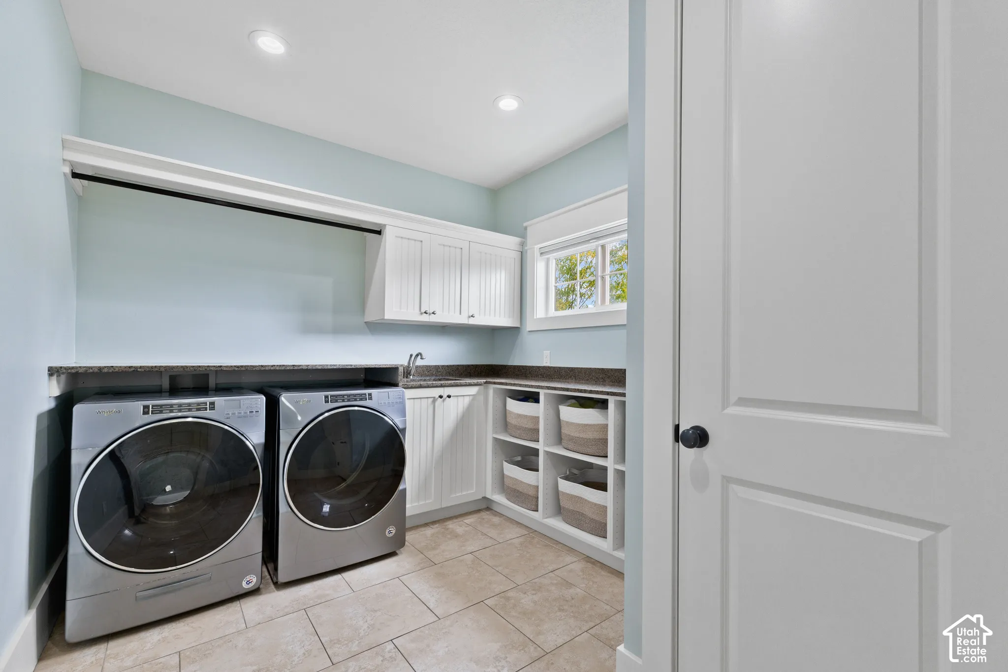 Laundry room featuring tile flooring, white shaker-style cabinetry, stone-finish countertops, an integrated sink, and open built-in shelving