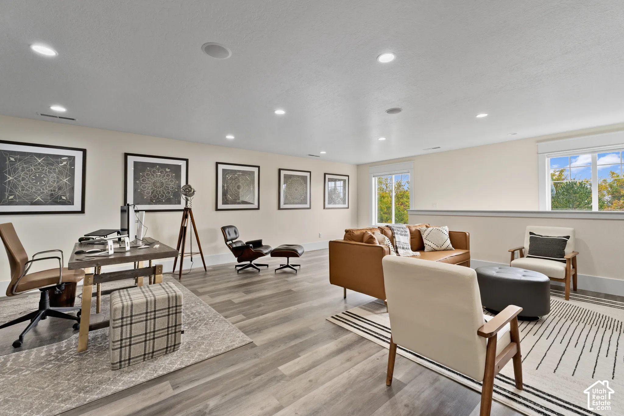 Spacious living area featuring wood-finish flooring, recessed lighting, and multiple windows
