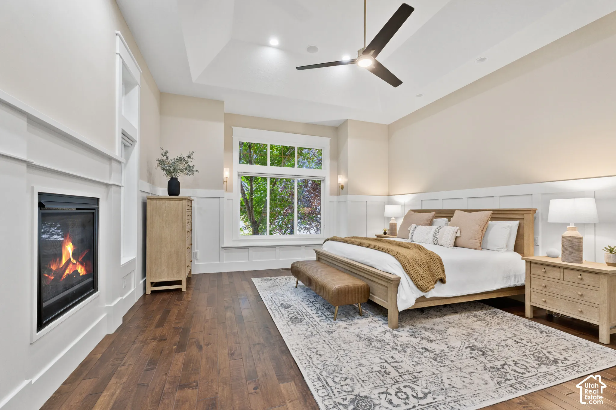 Tray ceiling with recessed lighting, wood-finish flooring, white wainscoting, and a built-in fireplace