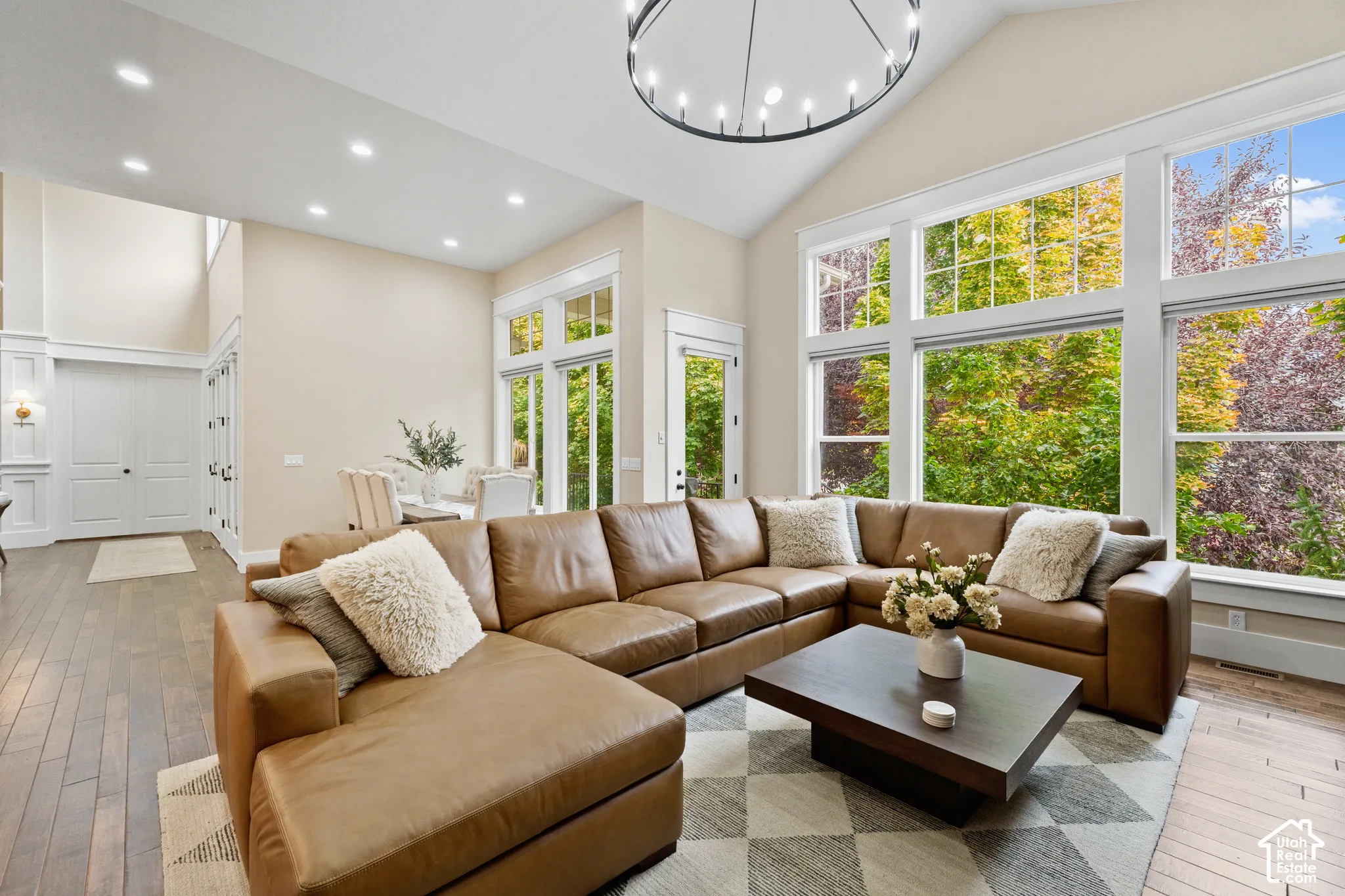Vaulted ceilings, large-pane windows, wood-finish flooring, recessed lighting, and a multi-tiered circular chandelier