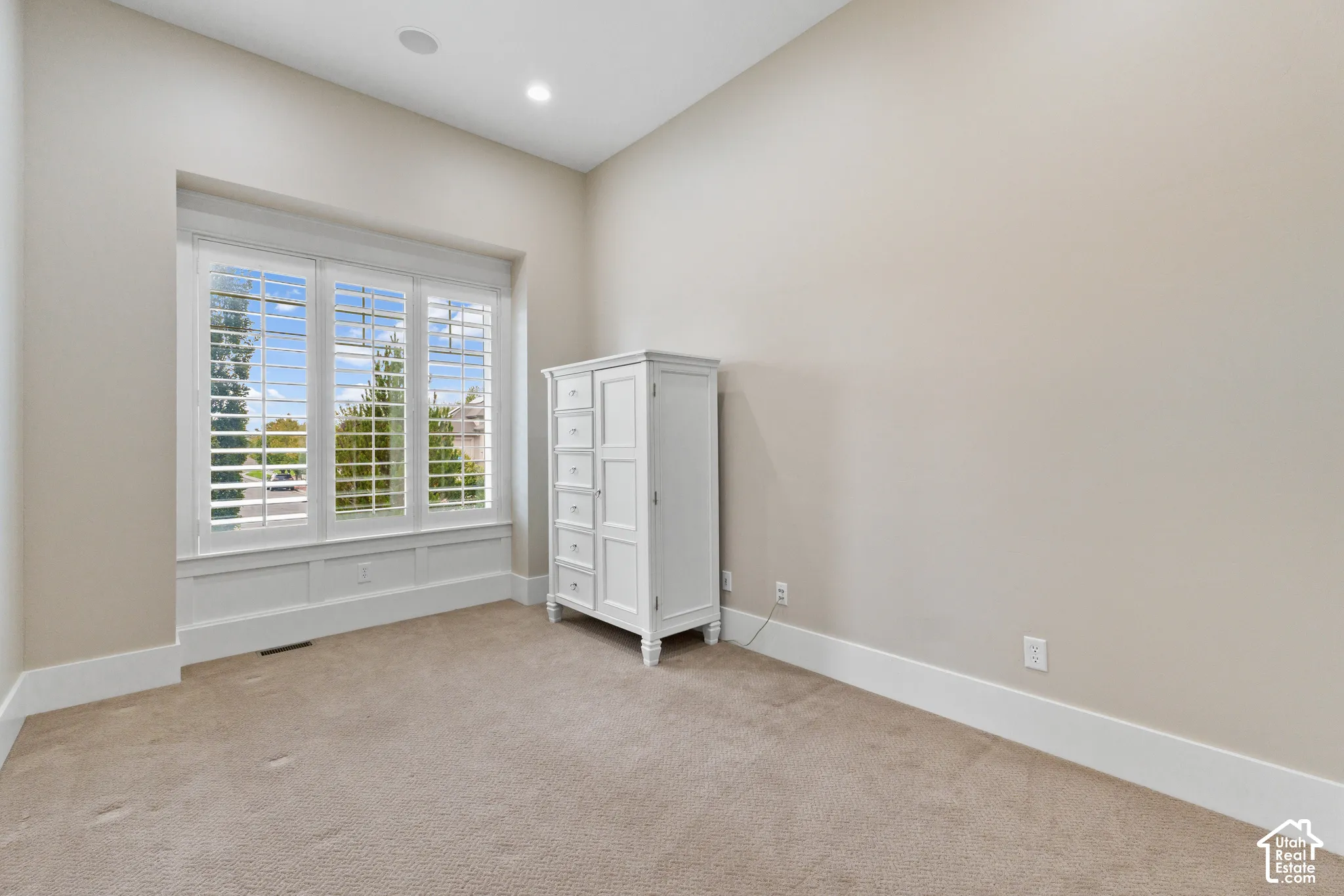 High ceilings featuring recessed lighting, a recessed triple-pane window alcove with plantation shutters, and wall-to-wall carpeting